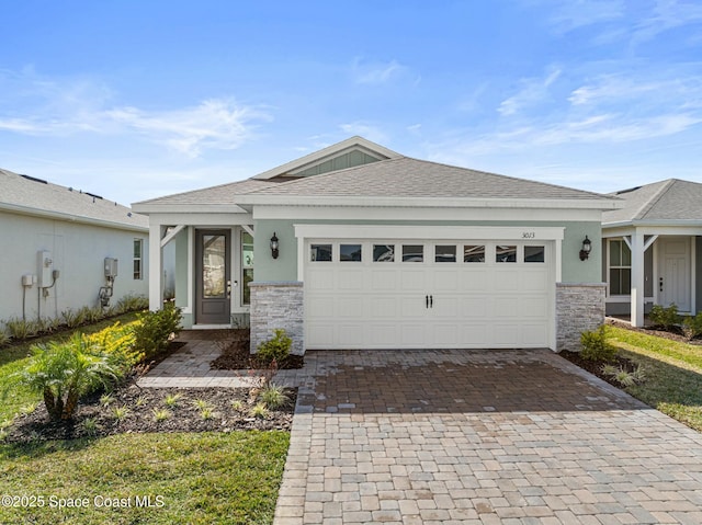 view of front of house featuring decorative driveway, roof with shingles, stucco siding, a garage, and stone siding