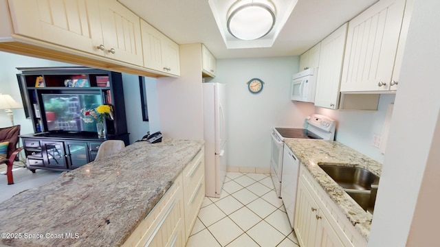 kitchen featuring a sink, white appliances, light tile patterned floors, baseboards, and light stone countertops