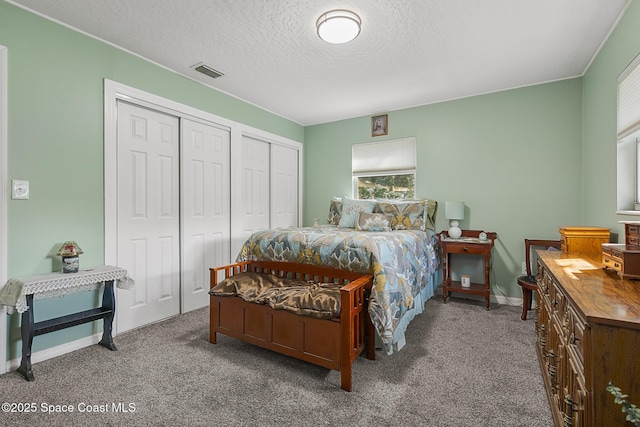 carpeted bedroom with baseboards, a textured ceiling, visible vents, and two closets