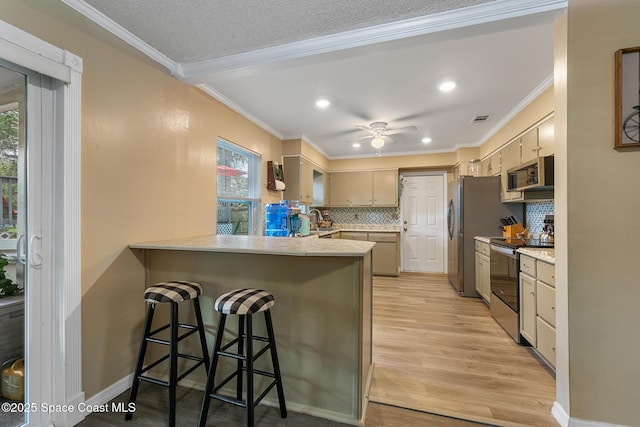 kitchen featuring light wood finished floors, visible vents, appliances with stainless steel finishes, ornamental molding, and a peninsula