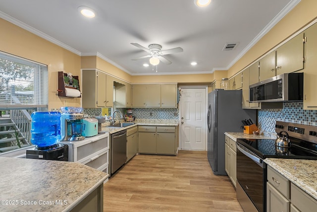 kitchen with light wood finished floors, visible vents, appliances with stainless steel finishes, crown molding, and a sink