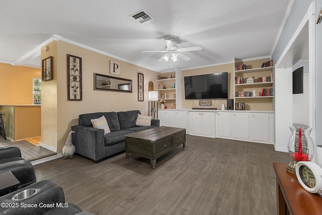 living area with a textured ceiling, ornamental molding, dark wood-style flooring, and visible vents