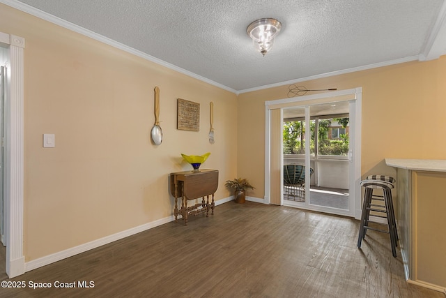 interior space with crown molding, a textured ceiling, baseboards, and wood finished floors