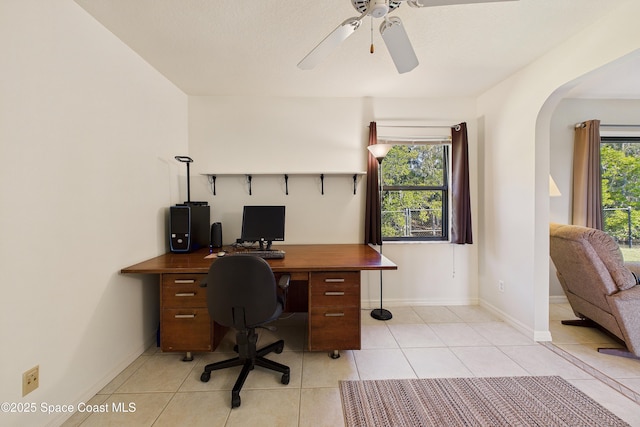 office featuring arched walkways, ceiling fan, light tile patterned flooring, and baseboards