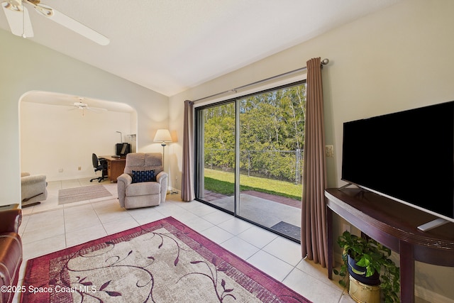 tiled living room featuring lofted ceiling, arched walkways, and a ceiling fan