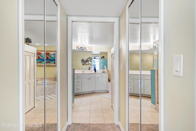 hallway with light tile patterned flooring, a sink, and light colored carpet