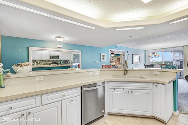 kitchen featuring stainless steel appliances, a sink, white cabinetry, light countertops, and an inviting chandelier