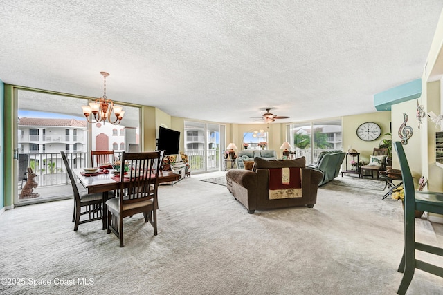 carpeted dining area featuring a textured ceiling, a wealth of natural light, and ceiling fan with notable chandelier