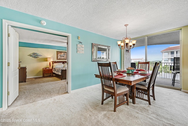 carpeted dining room with an inviting chandelier, baseboards, a wall of windows, and a textured ceiling