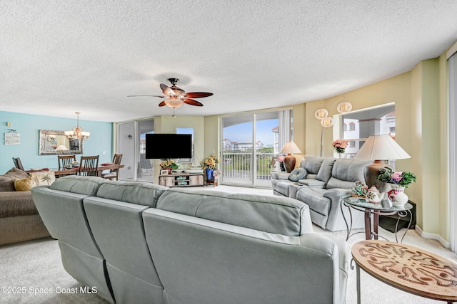 living area with baseboards, ceiling fan with notable chandelier, a textured ceiling, and light colored carpet