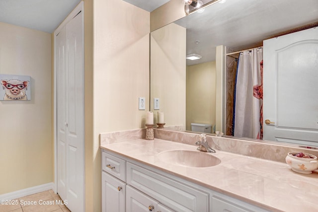 bathroom with a closet, toilet, vanity, baseboards, and tile patterned floors