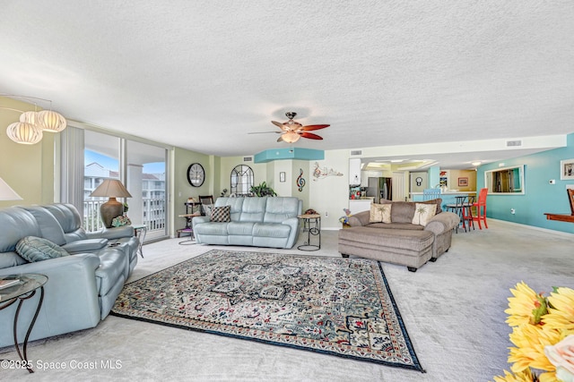 carpeted living area with ceiling fan, baseboards, and a textured ceiling