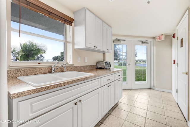 kitchen featuring french doors, white cabinets, and a sink