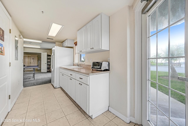 kitchen with light tile patterned floors, a toaster, light countertops, white cabinetry, and a sink