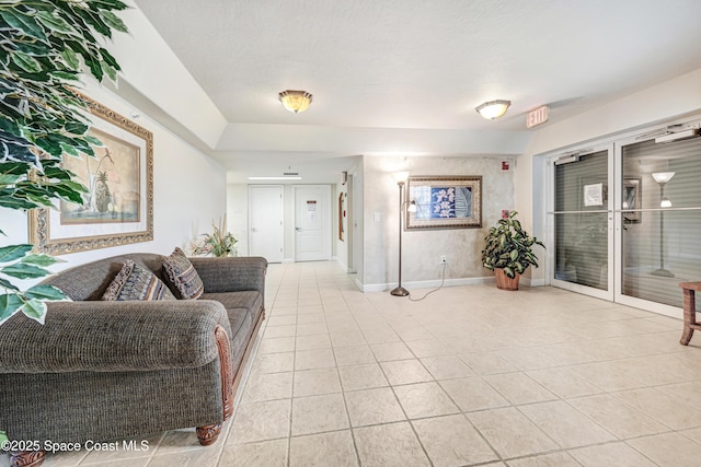 living room with light tile patterned floors, a textured ceiling, and baseboards