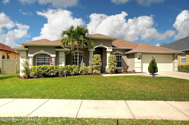 mediterranean / spanish-style home featuring a garage, driveway, a front lawn, and stucco siding