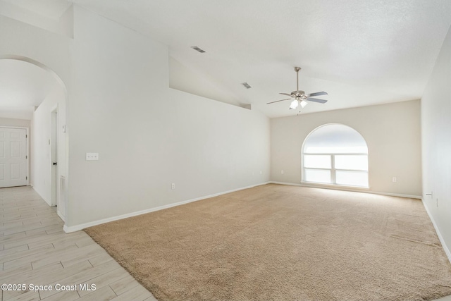 unfurnished room featuring baseboards, visible vents, arched walkways, and a ceiling fan