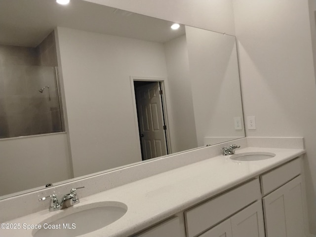 full bathroom featuring double vanity, tiled shower, a sink, and recessed lighting