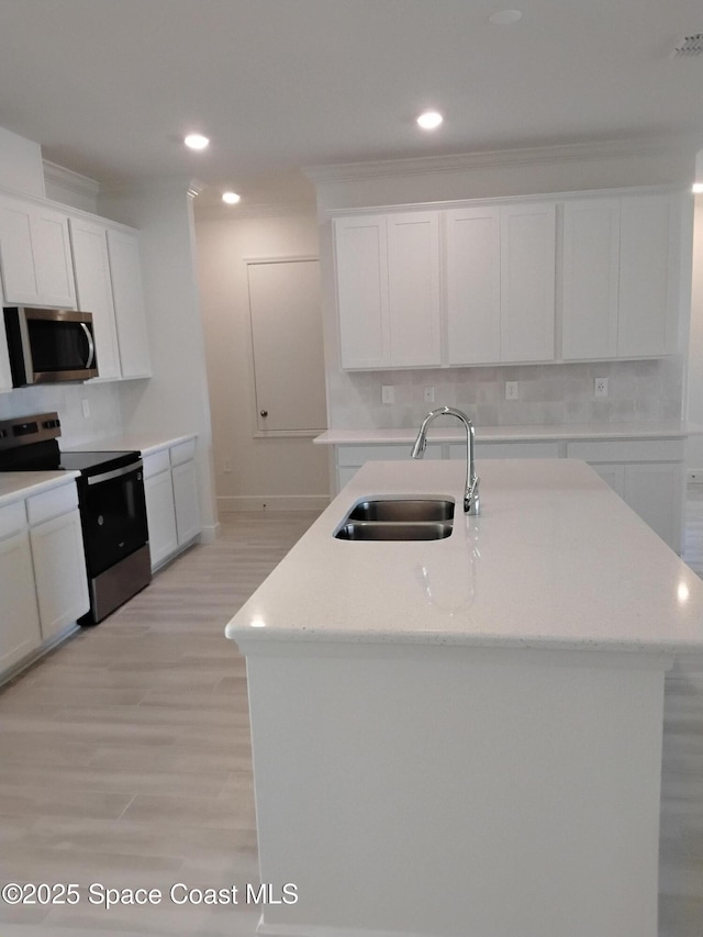 kitchen featuring appliances with stainless steel finishes, a sink, white cabinetry, and light wood-style floors