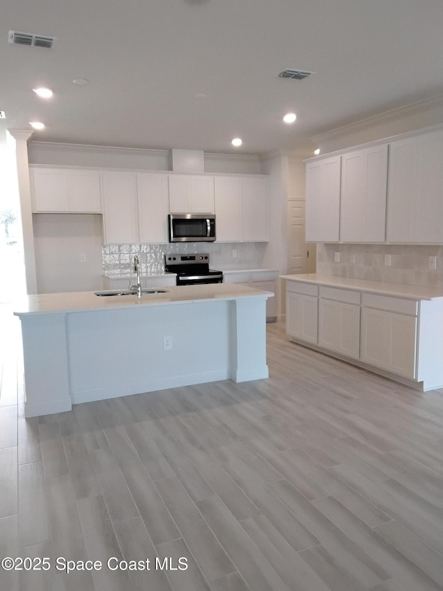 kitchen featuring appliances with stainless steel finishes, white cabinets, visible vents, and a sink