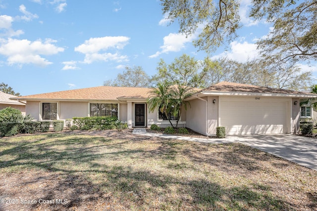 ranch-style home featuring a garage, a front yard, concrete driveway, and stucco siding