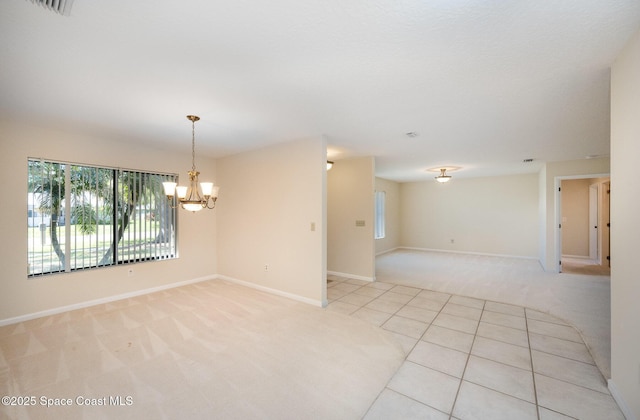 empty room with light tile patterned floors, visible vents, light carpet, a chandelier, and baseboards