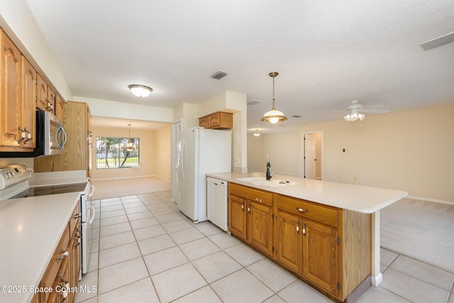 kitchen with light countertops, visible vents, a sink, white appliances, and a peninsula