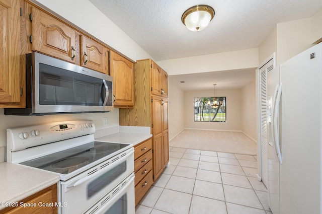 kitchen with a textured ceiling, light tile patterned floors, a notable chandelier, white appliances, and light countertops