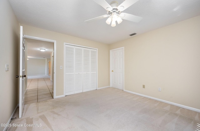 unfurnished bedroom featuring carpet floors, a closet, visible vents, ceiling fan, and baseboards