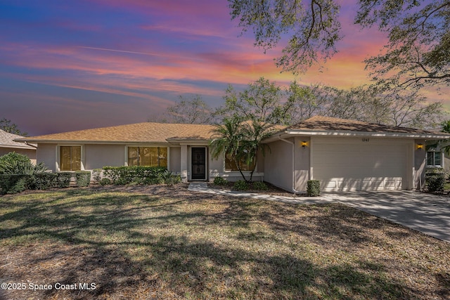 ranch-style home with an attached garage, a front lawn, concrete driveway, and stucco siding