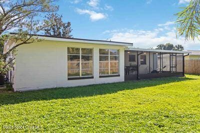 back of property with a sunroom and a lawn