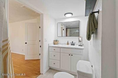 bathroom featuring toilet, wood finished floors, and vanity