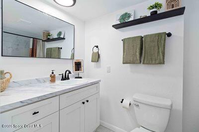 full bath with baseboards, a shower with shower curtain, vanity, and toilet