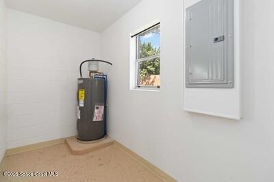 utility room featuring electric panel and water heater