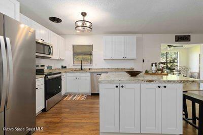 kitchen featuring a breakfast bar area, appliances with stainless steel finishes, white cabinetry, a sink, and a kitchen island