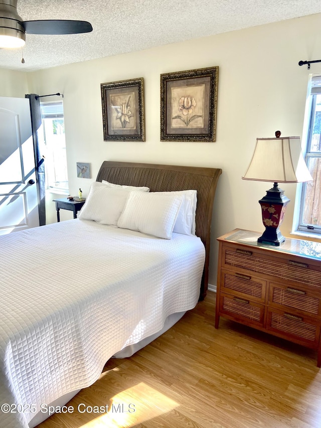 bedroom with multiple windows, a textured ceiling, and wood finished floors