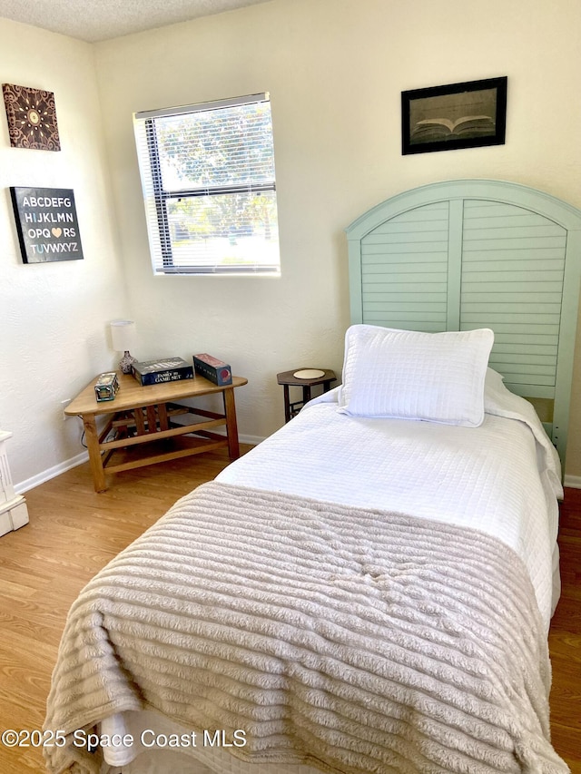 bedroom featuring a textured ceiling, baseboards, and wood finished floors