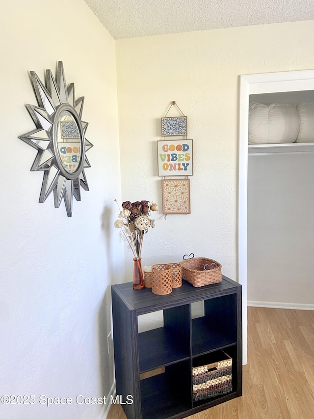 interior details with a textured ceiling, baseboards, and wood finished floors