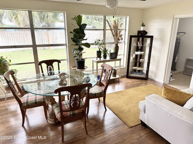 dining space with water heater, wood finished floors, and baseboards