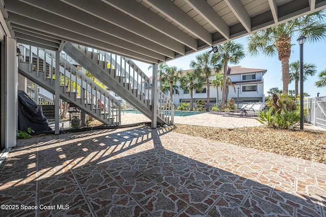 view of patio / terrace featuring fence, a community pool, and stairs