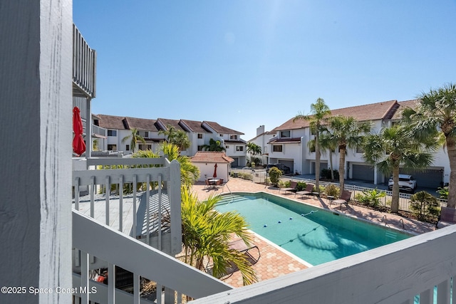 community pool with a patio area, a residential view, and fence