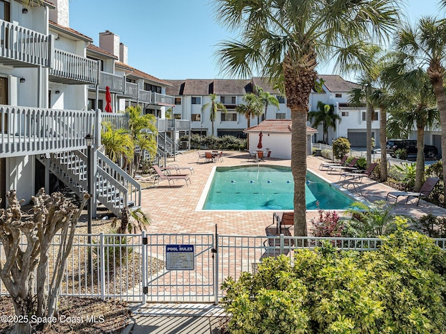 community pool featuring a residential view, a patio area, fence, and stairway