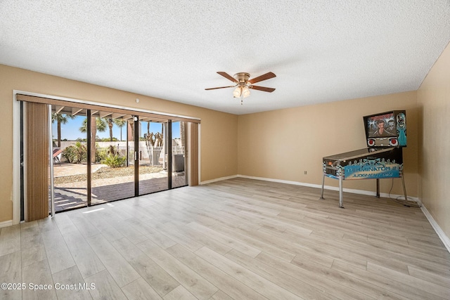 spare room featuring a ceiling fan, light wood-type flooring, a textured ceiling, and baseboards