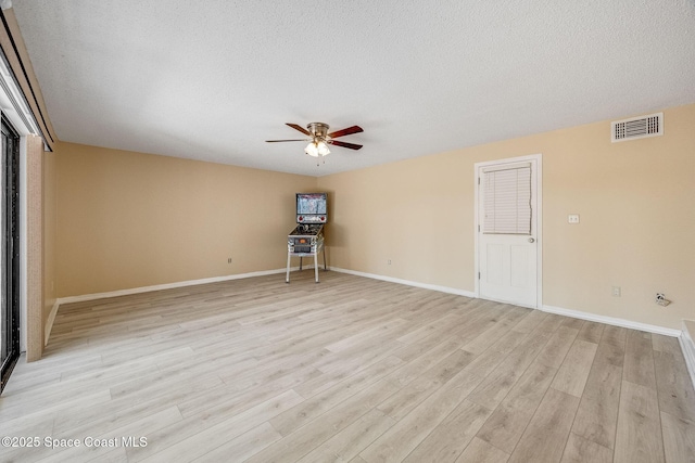 spare room with visible vents, light wood-style floors, ceiling fan, a textured ceiling, and baseboards