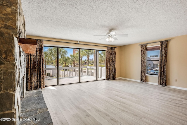 unfurnished living room featuring ceiling fan, a textured ceiling, baseboards, and wood finished floors