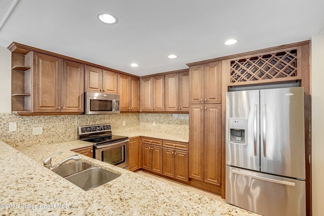 kitchen featuring decorative backsplash, light stone counters, stainless steel appliances, open shelves, and a sink