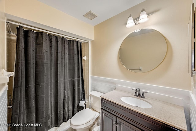 full bath with curtained shower, visible vents, toilet, wainscoting, and vanity