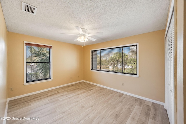 unfurnished bedroom featuring light wood-style floors, visible vents, baseboards, and multiple windows