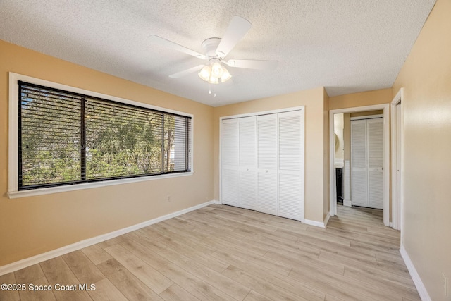 unfurnished bedroom featuring baseboards, a closet, a textured ceiling, and light wood-style floors