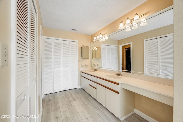 bathroom featuring a sink, visible vents, a closet, and wood finished floors